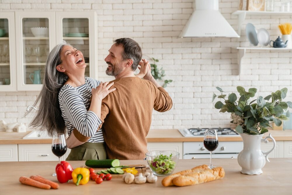 Laughing couple dancing together in their kitchen