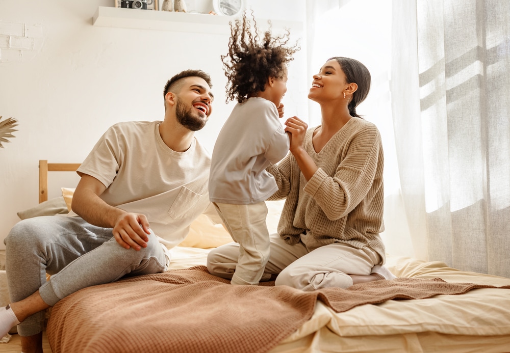 Parents playing with their young daughter on a bed