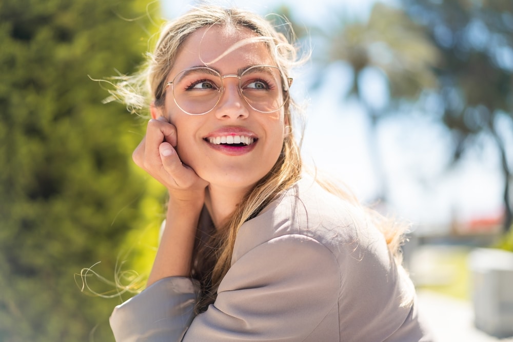 Smiling woman wearing glasses outdoors in the sun