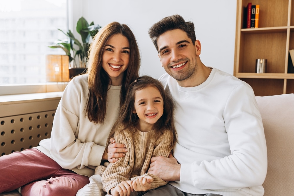 Smiling family of three sitting together on a sofa