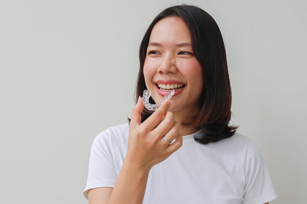 Smiling woman holding a clear aligner
